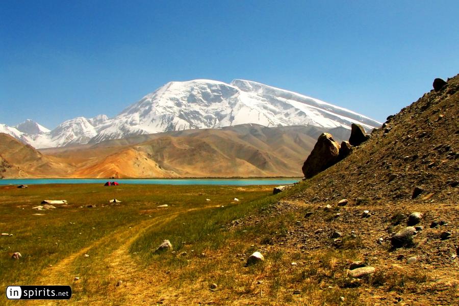Tents dwarved by Muztagh Ata at Karakul Lake