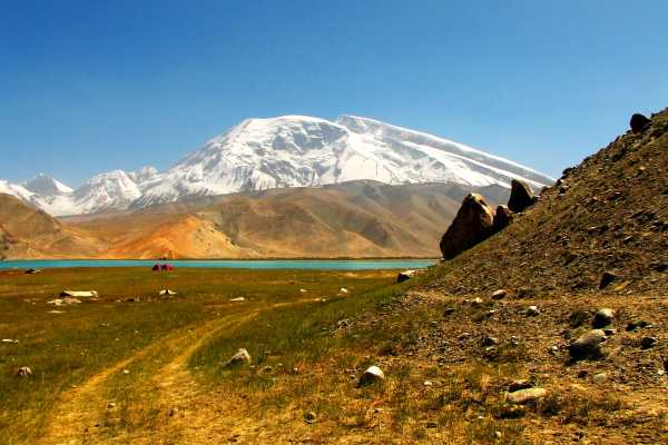 Tents dwarved by Muztagh Ata at Karakul Lake